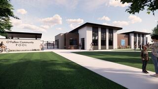 A modern community pool complex with lush green lawns, pathways, and people enjoying outdoor activities in a vibrant setting.