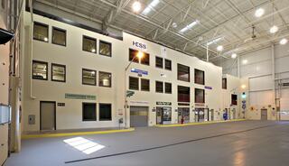 A spacious indoor facility with multiple rooms and large windows, featuring various signage and a polished concrete floor.