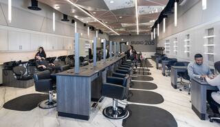 A modern salon features sleek stylist stations, comfortable chairs, and ample lighting, creating a welcoming atmosphere for customers.