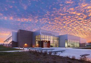 A modern Transportation Education Center stands against a vibrant sunset sky, showcasing its large windows and sleek architectural design.