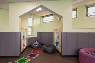 A cozy, colorful play area with seating, shelves for toys, and bright floor mats, designed for relaxation and creativity.