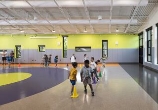 A vibrant indoor activity space features children engaging in play, navigating around colorful cones on a uniquely patterned floor.