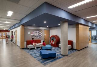 A modern, bright school lounge features colorful seating and children engaged in activities, promoting a collaborative learning environment.