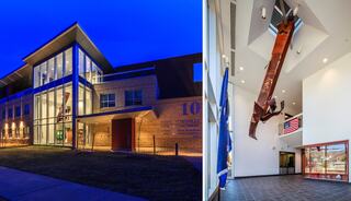 A modern building features large windows and an impressive entrance, with an exhibit of a massive steel structure hanging indoors.