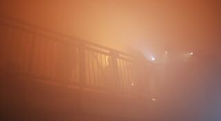 A dense fog engulfs a railing, silhouettes of people using flashlights emerge, creating a mysterious and atmospheric scene.