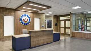 A modern reception area features a stylish desk, official seals, and flags, complemented by a neutral color palette and soft lighting.