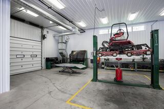 A clean, organized garage featuring a vehicle lift, tools, and a spacious area with bright lighting, suitable for maintenance work.