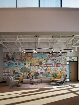 A modern church lobby and lounge features a vibrant mural, stylish furniture, and large windows, creating a cozy and inviting atmosphere.