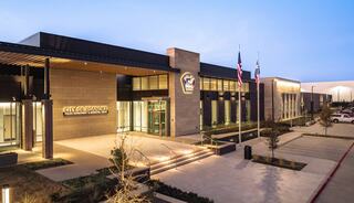 A modern municipal building featuring a sleek design, with flags and landscaped pathways, symbolizing civic pride and community service.