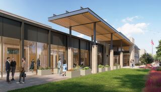 A modern building with large glass windows and a wooden overhang, featuring green landscaping and people gathering outside in a vibrant setting.