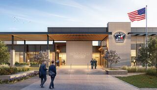 A modern police station with a welcoming entrance, featuring landscaped greenery, the American flag, and officers interacting in the vicinity.