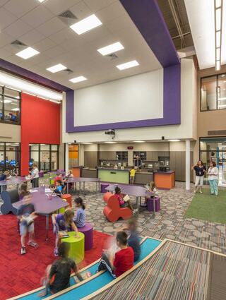 A vibrant, modern space filled with children engaged in activities, featuring colorful furniture and open areas for play and collaboration.