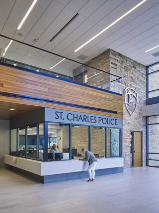 Modern police station lobby featuring a reception area with glass windows and natural wood accents, creating an inviting atmosphere.