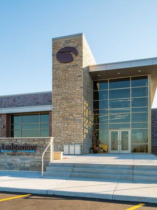 A modern building features a stone facade, large glass windows, and a welcoming entrance. The name "Ledgeview" is prominently displayed.