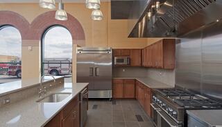 A modern kitchen with stainless steel appliances, wooden cabinets, and large windows, showcasing a spacious and well-equipped cooking area.