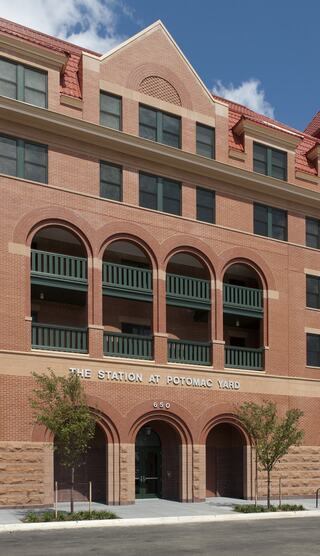 A brick building with a prominent entrance features arched windows and balconies. It's labeled "The Station at Potomac Yard."