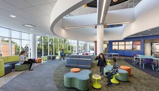 A bright, modern learning space features colorful seating and children engaged in activities, promoting collaboration and creativity.