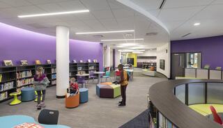 A vibrant library space features colorful seating, bookshelves, and playful design elements, fostering an inviting atmosphere for reading and learning.