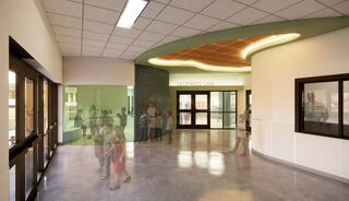 A modern hallway features a curved wall, bright lighting, and people mingling, creating a welcoming atmosphere in a communal space.