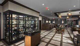 A stylish bar area features elegant seating and a glass display case filled with various bottles, creating a sophisticated atmosphere.