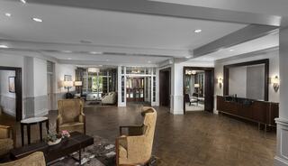 A spacious, well-lit lobby features elegant seating, tasteful decor, and warm wooden accents, creating a welcoming atmosphere.