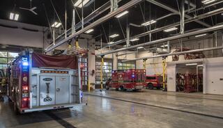 A spacious fire station with multiple fire trucks, an open layout, and modern features including overhead doors and equipment storage.
