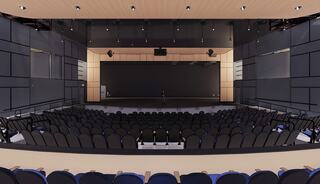 A modern auditorium features a spacious seating area, a polished stage with a large screen, and sleek black and wooden design elements.