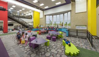 A colorful, modern children's library with playful furniture, large windows, and kids engaging in various activities. Bright and inviting space.