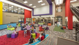 A vibrant, modern library space with colorful furniture where children engage in various activities, promoting learning and creativity.