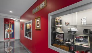 A vibrant red corridor showcases a display of firefighting memorabilia, including hats, photos, and artifacts, creating a historical ambiance.