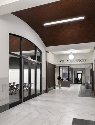 A modern office lobby with a spacious layout, glass doors, a reception area, and a stylish ceiling, featuring a neutral color palette.