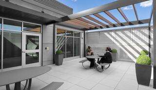 A stylish outdoor patio features modern seating, planters, and ample natural light, creating an inviting space for conversation and relaxation.