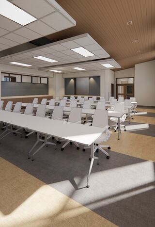 A modern classroom features white tables and ergonomic chairs arranged in rows, with ample natural light and a polished design.