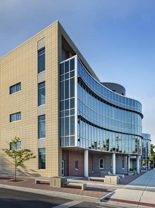 A modern educational building features a sleek, curved glass facade and a mix of materials, blending functionality with aesthetic appeal.