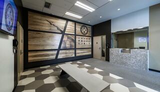 A modern, stylish reception area features hexagonal flooring, a wooden wall art display, and a sleek front desk with a granite finish.
