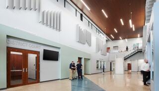 A spacious, modern court lobby features natural light, sleek design, and an inviting atmosphere, with staff engaged in conversation.