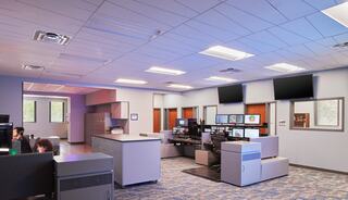 A modern control room features multiple screens, ergonomic workstations, and a spacious layout with soft lighting and a professional atmosphere.