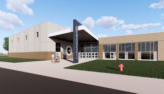 A modern building with a large entrance sign, surrounded by grass and sidewalks, features a vibrant, welcoming atmosphere.