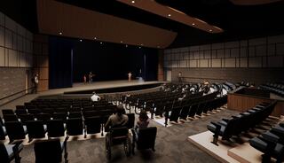 A spacious auditorium with tiered seating, stage lights, and an audience gathered, creating a setting for a presentation or event.