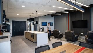 A modern, open-plan kitchen and lounge area features sleek appliances, comfortable seating, and a contemporary design.