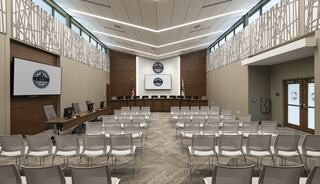 A modern meeting room featuring rows of chairs, a central podium, screens, and decorative wall elements, designed for official gatherings.