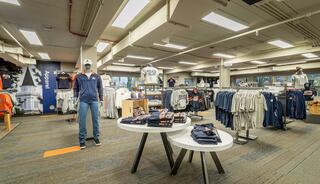 A spacious store features apparel displays, including shirts and sweatshirts, with mannequins showcasing various outfits.