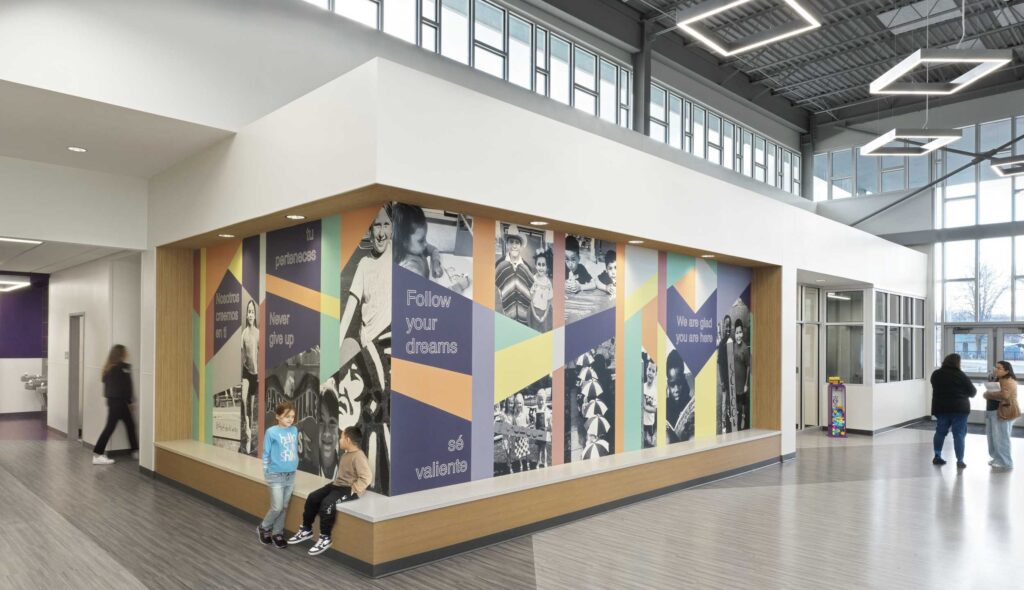 A modern interior features colorful murals promoting inspiration and dreams, with children and adults engaged in activities nearby.