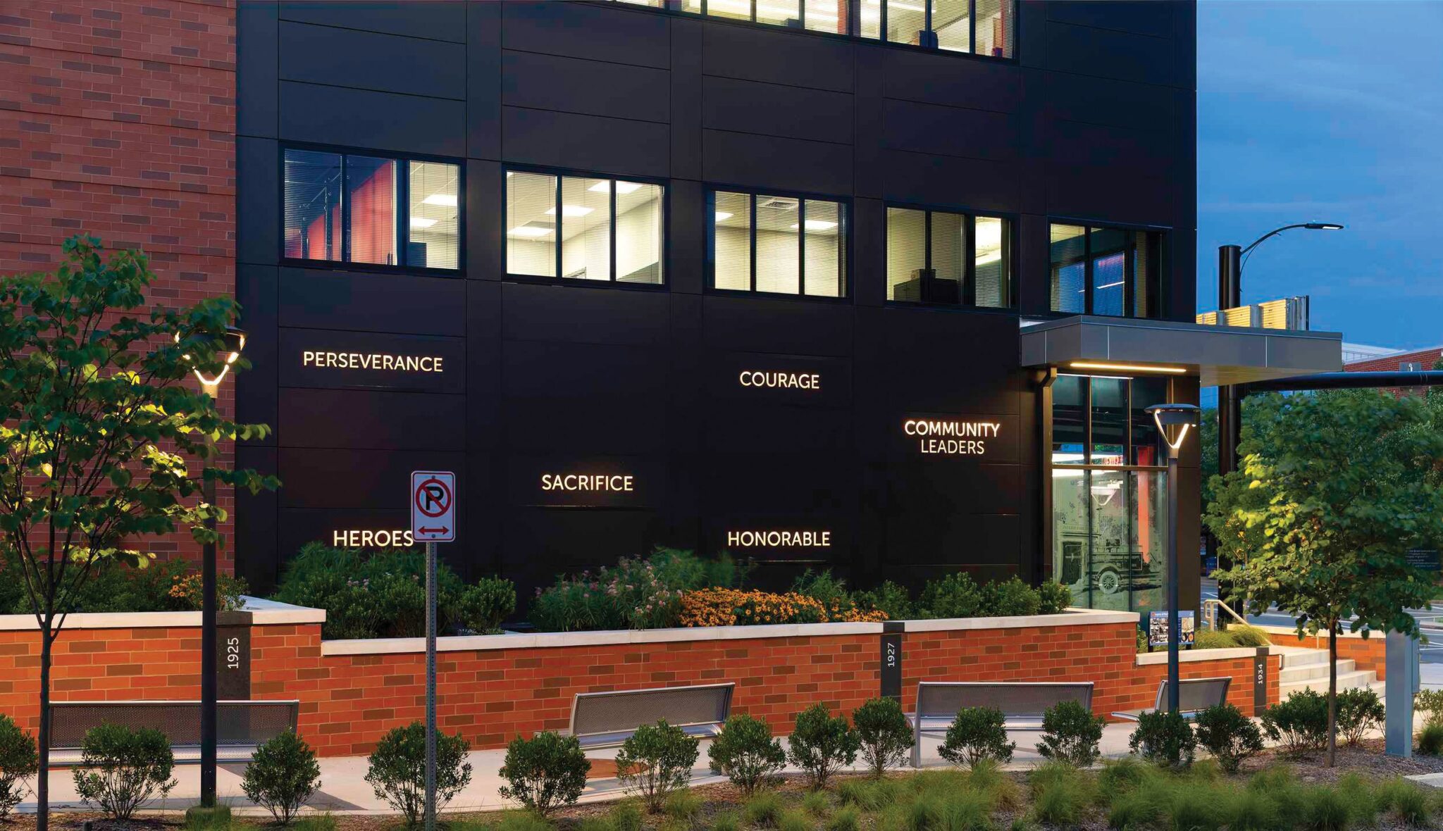 A fire station features inspirational words like "Perseverance," "Courage," and "Community Leaders" on its exterior, surrounded by greenery.