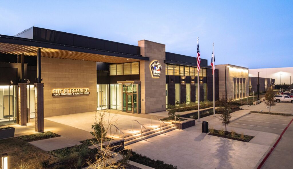A modern municipal building featuring a sleek design, with flags and landscaped pathways, symbolizing civic pride and community service.