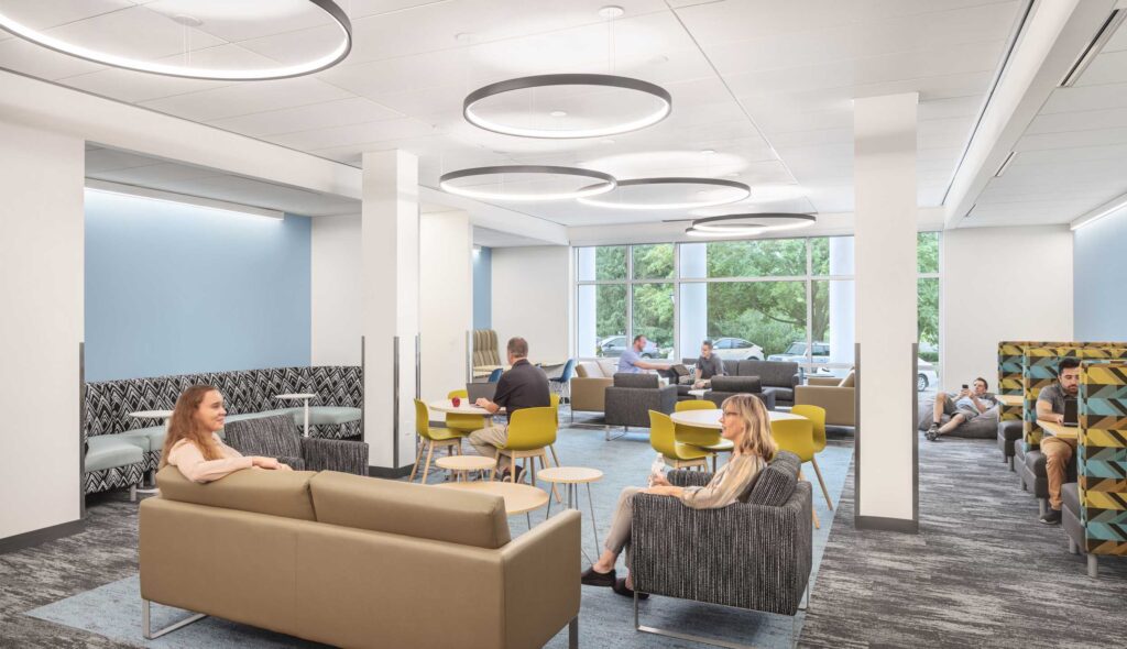 A modern lounge area features comfortable seating, large windows, and circular light fixtures, creating a relaxed atmosphere for socializing or studying.