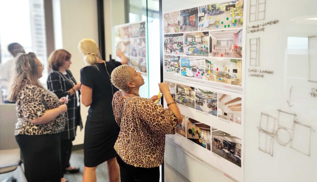 A group of professionals collaborates in a modern workspace, reviewing design concepts displayed on boards, exchanging ideas and insights.