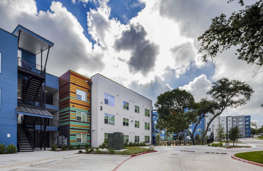 Modern multi-story affordable housing buildings featuring colorful facades and landscaped surroundings.