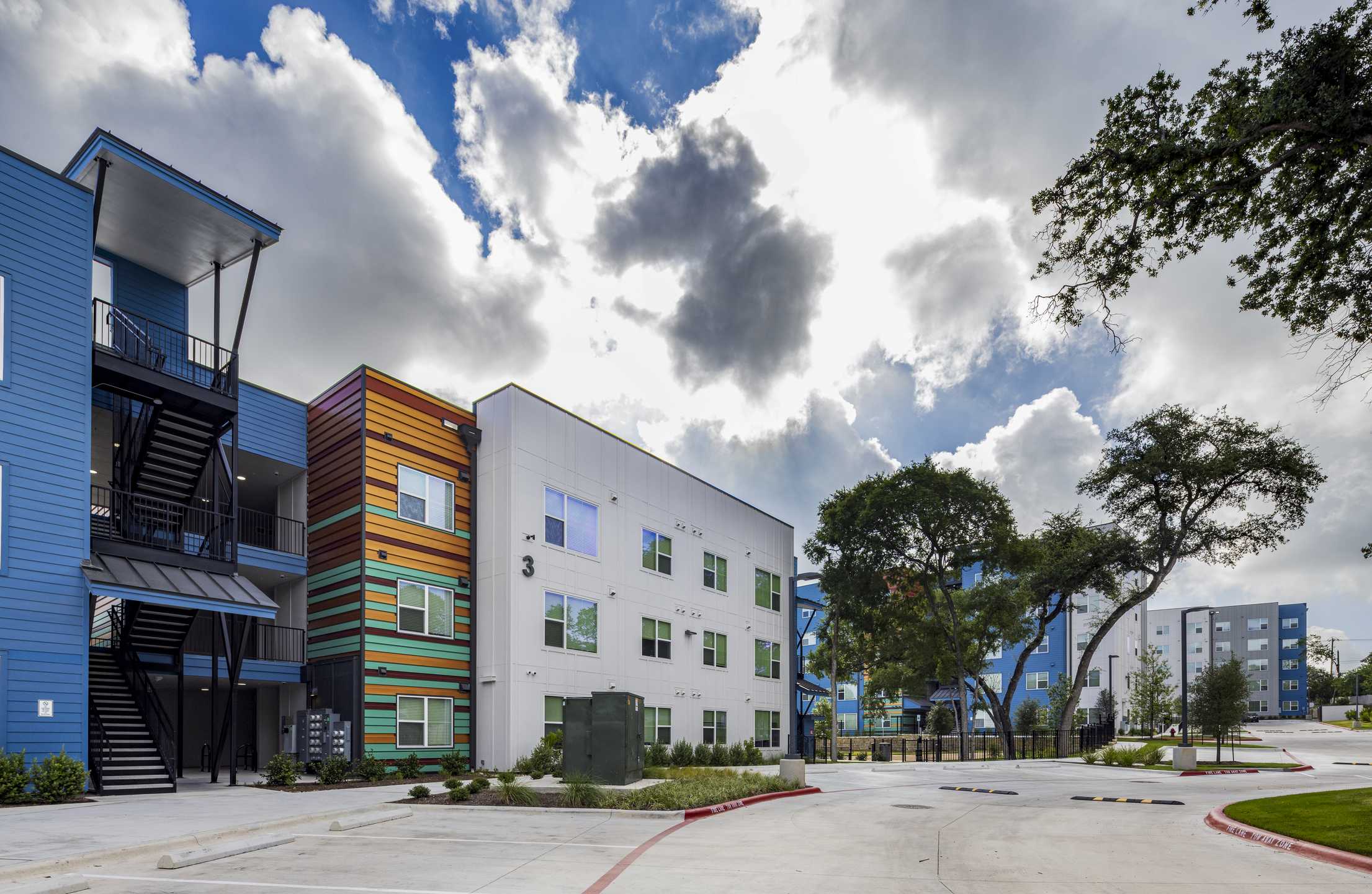 Modern multi-story affordable housing buildings featuring colorful facades and landscaped surroundings.