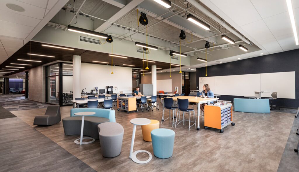A modern classroom with flexible seating, collaborative workstations, and bright colors, promoting a dynamic learning environment.